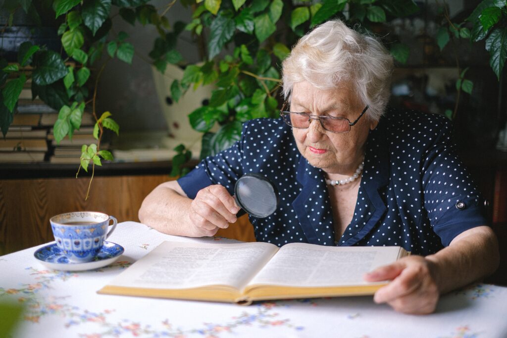 A lady using a magnifying glass to read a book
